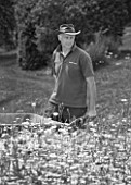 BLACK AND WHITE IMAGE OF WHATLEY MANOR  WILTSHIRE: HEAD GARDENER BARRY HOLMAN IN THE SPA GARDEN WITH  ANNUAL WILDFLOWER MEADOW