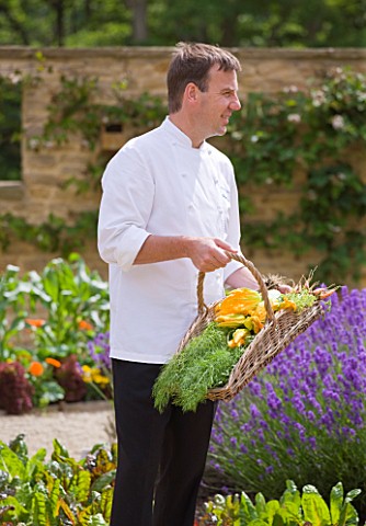 WHATLEY_MANOR__WILTSHIRE_HEAD_CHEF_MARTIN_BURGE_WITH_A_TRUG_FILLED_WITH_VEGETABLES_IN_THE_KITCHEN_GA