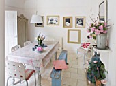 AMANDA KNOX HOUSE  GRANTHAM: THE DINING ROOM - WHITE WITH HINTS OF PINK - TABLE WITH OILCLOTH TABLECLOTH  CHAIRS FROM IKEA   FADED BLUE WOODEN BENCH  FAMILY PORTRAITS IN OLD FRAMES