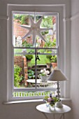 AMANDA KNOX HOUSE  GRANTHAM: THE DINING ROOM - WHITE WITH HINTS OF PINK - LARGE SASH WINDOW LOOKING OUT INTO COURTYARD. TABLE WITH LAMP  STAR DECORATION IN WINDOW