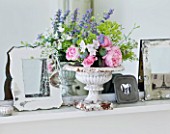 AMANDA KNOX HOUSE  GRANTHAM: THE WHITE SITTING ROOM - MANTELPIECE ABOVE FIREPLACE WITH PHOTO FRAMES  A VINTAGE WHITE METAL GARDEN URN WITH FRESH FLOWERS