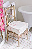 AMANDA KNOX HOUSE  GRANTHAM:WHITE KITCHEN WITH TRADITIONAL ROLL TOP BATH  OLD BAMBOO CHAIR COVERED WITH VINTAGE FLORAL PRINT CUSHION. ROSE PRINTED FLOOR TILES FROM IKEA