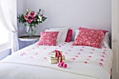 DESIGNER JACKY HOBBS  LONDON - WHITE BEDROOM AT CHRISTMAS WITH PRESENT ON BED AND RED PILLOWS