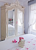 DESIGNER JACKY HOBBS  LONDON - WHITE BEDROOM AT CHRISTMAS WITH PRESENT ON BED AND MIRROR FRONTED WARDROBE