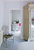 DESIGNER JACKY HOBBS  LONDON - WHITE BEDROOM AT CHRISTMAS WITH MIRROR FRONTED WARDROBE AND VIEW THROUGH TO BATHROOM BEYOND