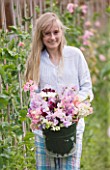 THE GARDEN AND PLANT COMPANY  HATHEROP CASTLE  CIRENCESTER  GLOUCESTERSHIRE: GIRL WITH BUCKET FULL OF FRESHLY PICKED SWEET PEAS FROM THE NURSERY