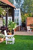 ULTING WICK  ESSEX - THE GARDEN IN AUTUMN - VIEW TO GREENHOUSE WITH WHITE SEAT  CONTAINERS PLANTED WITH AEONIUM SCHWARZKOPF AND BRUGMANSIA