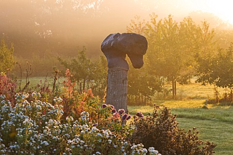 WATERPERRY_GARDENS__OXFORDSHIRE_THE_TRIAL_BEDS_AT_DAWN_WITH_SCULPTURE_EMERGING_FROM_MIST