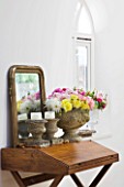 JACKY HOBBS HOUSE  LONDON: STONE INDOOR URN FILLED WITH MIXED DAHLIA BOUQUET WITH STONE CANDLE PLINTHS AND MIRROR ON WOODEN DESK
