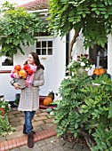 JACKY HOBBS HOUSE  LONDON: JACKY HOBBS WITH BUCKET FULL OF BRIGHT AUTUMNAL DAHLIA BLOOMS OUTSIDE HER HOME WITH PUMPKIN ON THE DOORSTEP