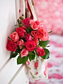 JACKY HOBBS HOUSE  LONDON: ROSE PRINTED FABRIC BAG FILLED WITH DEEP PINK ROSEBUDS HANGING FROM DOOR IN PINK BEDROOM