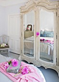 JACKY HOBBS HOUSE  LONDON: PINK DAHLIAS DECORATE THE PALE GREY FRENCH STYLE BEDROOM WITH MIRROR FRONTED WARDROBE