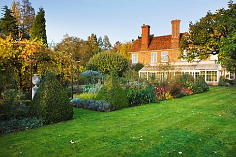 SALING_HALL__ESSEX__VIEW_ACROSS_THE_LAWN_TO_THE_HOUSE_AND_CONSERVATORY_WITH_URN_ON_PLINTH_AND_VINE_I
