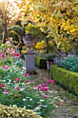 SALING HALL  ESSEX: AUTUMN BORDER LIT BY EVENING SUN WITH URN ON PLINTH BEHIND