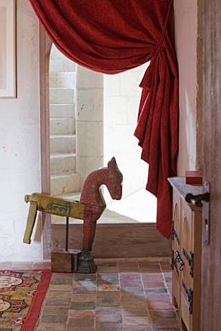 CHATEAU_DU_RIVAU__LOIRE_VALLEY__FRANCE_RED_THEMED_BEDROOM__WOODEN_HORSE_BY_STAIRCASE