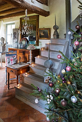 ROQUELIN__LOIRE_VALLEY__FRANCE_CHRISTMAS_TREE_AT_THE_FOOT_OF_WOODEN_STAIRCASE_IN_THE_SITTING_ROOM