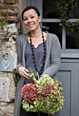ROQUELIN  LOIRE VALLEY  FRANCE: OWNER ALINE CHASSINE WITH HYDRANGEAS OUTSIDE THE FRONT DOOR OF THE FARMHOUSE