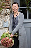 ROQUELIN  LOIRE VALLEY  FRANCE: OWNER ALINE CHASSINE WITH HYDRANGEAS OUTSIDE THE FRONT DOOR OF THE FARMHOUSE