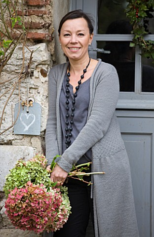 ROQUELIN__LOIRE_VALLEY__FRANCE_OWNER_ALINE_CHASSINE_WITH_HYDRANGEAS_OUTSIDE_THE_FRONT_DOOR_OF_THE_FA