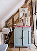 ROQUELIN  LOIRE VALLEY  FRANCE: BATHROOM; A SMALL BATHROOM FITS UNDER THE ROOF EAVES WITH PAINTED WOODEN CUPBOARD AND METAL TOWEL HOLDER