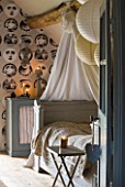 ROQUELIN  LOIRE VALLEY  FRANCE: BEDROOM; PAINTED WOODEN FRENCH BED DRESSED IN VINTAGE TOILLE DE JOUEY PRINTED QUILT. BEAMED CEILING AND PRINTED BLACK AND WHITE FACES WALLPAPER