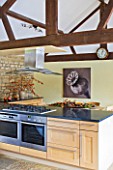 RICKYARD BARN HOUSE  OXFORDSHIRE: DESIGNERS JANE AND CLIVE NICHOLS. KITCHEN WITH SEPIA TONE PHOTO CANVAS BY CLIVE NICHOLS ON KITCHEN WALL WITH DRIED FRUIT DISPLAY ON TABLE