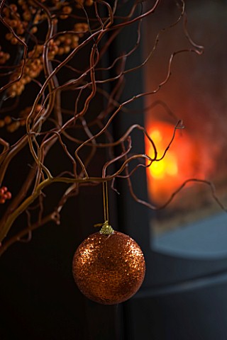 RICKYARD_BARN_HOUSE__OXFORDSHIRE_DESIGNERS_JANE_AND_CLIVE_NICHOLS_TWIGS_AND_BAUBLE_IN_FRONT_OF_FIRE_