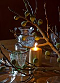 RICKYARD BARN HOUSE  OXFORDSHIRE: DESIGNERS JANE AND CLIVE NICHOLS. CHRISTMAS DECORATION ON DINING TABLE WITH CANDLES AND FIG BRANCH CUT FROM THE GARDEN