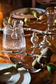 RICKYARD BARN HOUSE  OXFORDSHIRE: DESIGNERS JANE AND CLIVE NICHOLS. CHRISTMAS DECORATION ON DINING TABLE WITH CANDLES AND FIG BRANCH CUT FROM THE GARDEN