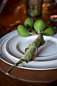 RICKYARD BARN HOUSE  OXFORDSHIRE: DESIGNERS JANE AND CLIVE NICHOLS. CHRISTMAS DECORATION ON DINING TABLE WITH FIG BRANCH CUT FROM THE GARDEN USED AS A NAPKIN HOLDER