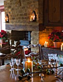 RICKYARD BARN  OXFORDSHIRE: CHRISTMAS - LIVING ROOM - DINING TABLE DECORATED WITH CANDLES  FIGS AND FIG LEAVES CUT FROM THE GARDEN