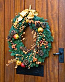 RICKYARD BARN  OXFORDSHIRE: CHRISTMAS - WREATH WITH BERRIES  FRUIT AND FIR CONES ON FRONT DOOR