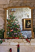 FULBROOK HOUSE: GALLERIED MAIN HALL GILT MIRROR ABOVE STONE FIREPLACE REFLECTING CHRISTMAS TREE