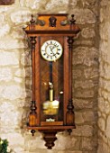 FULBROOK HOUSE: ANTIQUE WOODEN WALL CLOCK HANGS IN COTSWOLD STONE HALLWAY