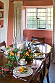 FULBROOK HOUSE: DINING ROOM; TERRACOTTA PAINTED WALLS WITH COTSWOLD STONE FLOOR  POLISHED WOOD TABLE SET WITH SEASONAL FLOWERS AND FOLIAGE