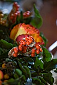 FULBROOK HOUSE: DINING ROOM; CHRISTMAS TABLE WREATH AND CANDLE CENTREPIECE WITH ORANGE/YELLOW ROSES AND BERRIES OF IRIS FOETIDISSIMA