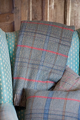 FULBROOK_HOUSE_SITTING_ROOM__ARMCHAIR_WITH_WOOL_PLAID_THROWS_AND_CUSHION_FROM_COTSWOLD_WOOLLEN_WEAVE