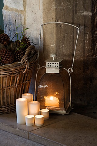 FULBROOK_HOUSE_SITTING_ROOM__COTSWOLD_STONE_FIRE_HEARTH_WITH_LOG_BASKET__METAL_LANTERN_AND_CANDLES