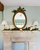 FULBROOK HOUSE: MASTER BEDROOM; COTSWOLD STONE MANTELPIECE WITH ANTIQUE GILT MIRROR TRIMMED WITH PINE FOR CHRISTMAS