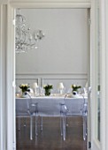 WHITE HOUSE: WHITE DINING ROOM WITH CENTRAL GLASS CHANDELIER AND LONG DINING TABLE DRESSED IN WHITE LINEN WITH TRANSPARENT GHOST CHAIRS