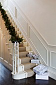 WHITE HOUSE: RECEPTION HALL: MAIN STAIRCASE  WHITE PANELLED WALLS  BANISTER DRESSED WITH CHRISTMAS PINE AND CONE GARLAND  PRESENTS ON STAIRS