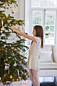 WHITE HOUSE: GIRL IN LIVING ROOM PUTTING DECORATIONS ON CHRISTMAS TREE