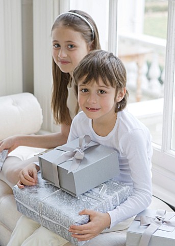 WHITE_HOUSE_GIRL_AND_BOY_IN_DINING_ROOM_SITTING_ON_WINDOW_SEAT_WITH_CHRISTMAS_PRESENTS