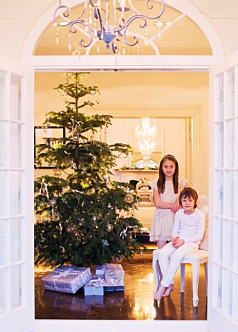 WHITE_HOUSE_VIEW_THROUGH_DOUBLE_FRENCH_DOORS_INTO_LIVING_ROOM__BOY_AND_GIRL_ON_SEAT_WITH_CHRISTMAS_T