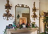 SARAH BAKERS HOUSE  THE OLD VICARAGE  SOMERSET: SITTING ROOM MANTLEPIECE WITH METAL WALL CANDLE SCONCES AND MIRROR  DECORATED WITH IVY FOR CHRISTMAS.