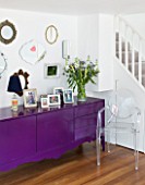 TARA NASH-KING HOUSE  LONDON: LIVING ROOM - VINTAGE MIRRORS DISPLAYED ABOVE BLACK CABINET PAINTED WITH PURPLE GLOSS PAINT  PHILIPPE STARCK GHOST CHAIR