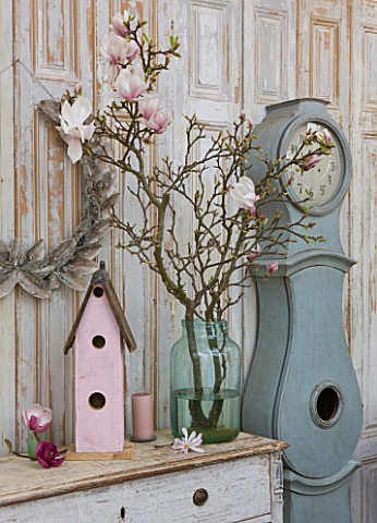 PETERSHAM_NURSERIES__RICHMOND__SURREY_DRESSER_WITH_MAGNOLIA_IN_GLASS_CONTAINER_WITH_BIRD_HOUSE_AND_B