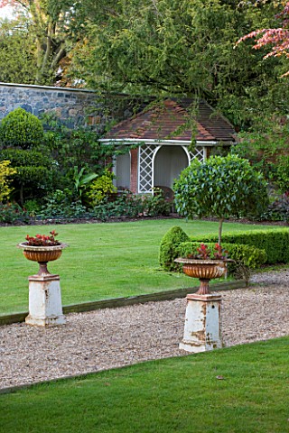 GRANGE_COURT__GUERNSEY_URNS_ON_PEDESTALS_BESIDE_PATH_AND_LAWN_WITH_SUMMER_HOUSE_IN_BACKGROUND