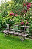 LES JARDINS DE ROQUELIN  LOIRE VALLEY  FRANCE: LAWN AND A DECORATIVE WOODEN CHESTNUT SEAT/ BENCH BY STEPHANE CASSINE BESIDE ROSE HENRI MARTIN AND ROSE MARIA LISA
