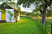 GIPSY HOUSE  BUCKINGHAMSHIRE: TLAWN  METAL FENCE  MEADOW AND ROALD DAHLS WHITE WRITING SHED WITH YELLOW DOOR